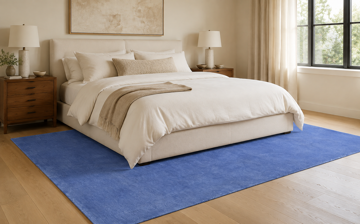 Placid Blue wool area rug staged beneath a bed in a modern neutral bedroom